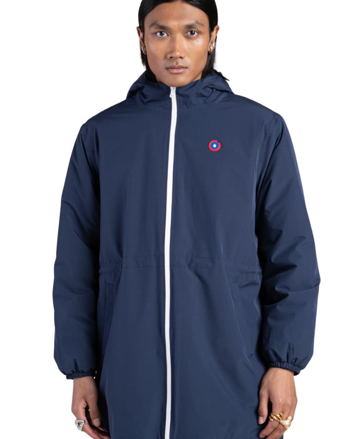 Parka imperméable mixte bleu indigo pour homme et femme, modèle Pompidou de la marque Flotte. Présente une coupe ajustée avec cordon de serrage à la taille, fermetures zippées étanches et doublure en polaire chaude.
