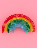 Pince à cheveux crabe de taille moyenne de la marque Coucou Suzette en acétate de cellulose brillant. L'accessoire prend la forme d'un arc-en-ciel incurvé aux bandes colorées et nacrées dans les tons rouge, jaune, vert, bleu et violet.
