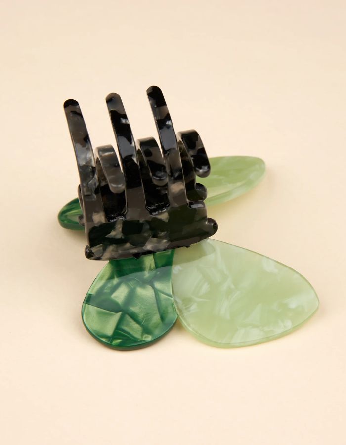 Gros plan sur la Pince à cheveux crabe de taille moyenne de la marque Coucou Suzette en acétate de cellulose brillant. L'accessoire prend la forme d'un papillon vert émeraude et vert menthe nacré aux ailes déployées avec des contours graphiques noirs