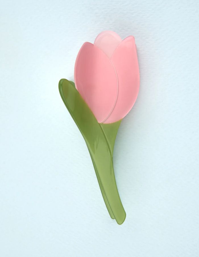Pince à cheveux crabe de la marque Coucou Suzette en acétate de cellulose brillant. L'accessoire prend la forme d'une tulipe graphique de couleur rose avec des feuilles vert tendre.