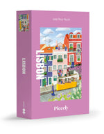 Puzzle de 1000 pièces pour adulte illustré par Mélanie Voituriez pour Piecely, représentant une rue colorée de Lisbonne avec le tramway jaune traditionnel et des façades en azulejos. Présenté aux côtés de sa boîte de rangement écoresponsable.