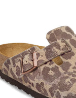 Boucle des Sabots fermés pour femme de style Boston de la marque Birkenstock, déclinés dans un imprimé léopard sauvage marron et sable Leo Sandcastle. Confectionnés en cuir velours doux avec une bride réglable à boucle métallique noire et la célèbre semelle anatomique en liège naturel.