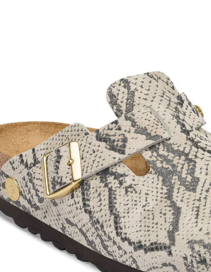 Boucle des Sabots fermés modèle Boston de la marque Birkenstock pour femme. La tige est en cuir velours souple beige clair avec un motif effet peau de serpent (Snake Oyster), dotée d'une bride réglable avec boucle métallique et montée sur une semelle anatomique en liège.