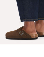 Vue portée des Sabots fermés modèle Boston de la marque Birkenstock en cuir velours souple de couleur marron foncé Carafe. Présente une bride ajustable à boucle métallique sur le dessus et une semelle anatomique ton sur ton en liège avec lit de pied souple, version chaussant étroit.