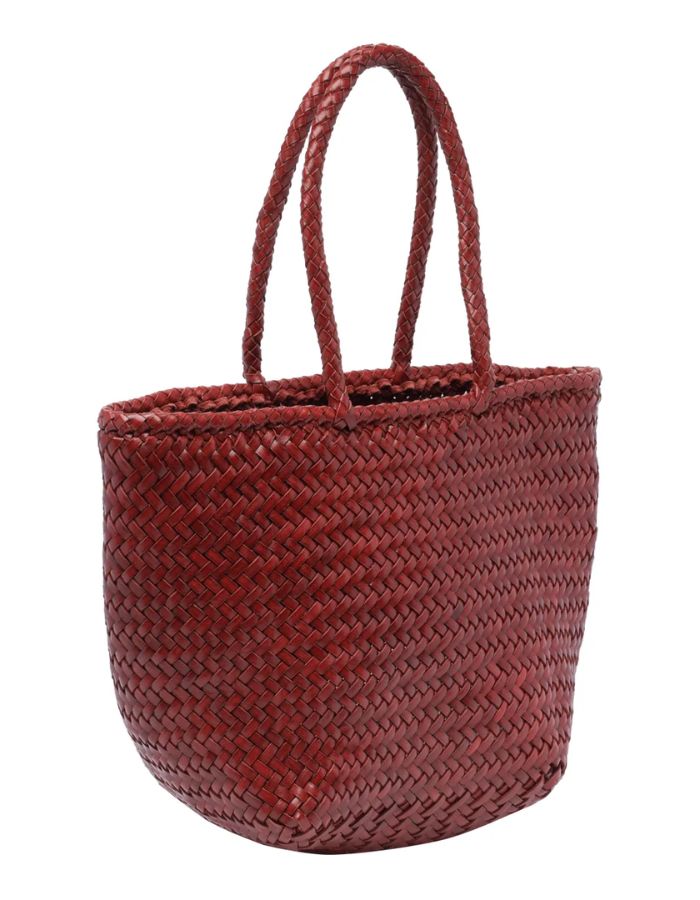 Vue du côté du petit sac panier Grace Basket de Dragon Diffusion en cuir tressé bordeaux, forme arrondie galbée avec tissage en diagonale et poignées tressées.