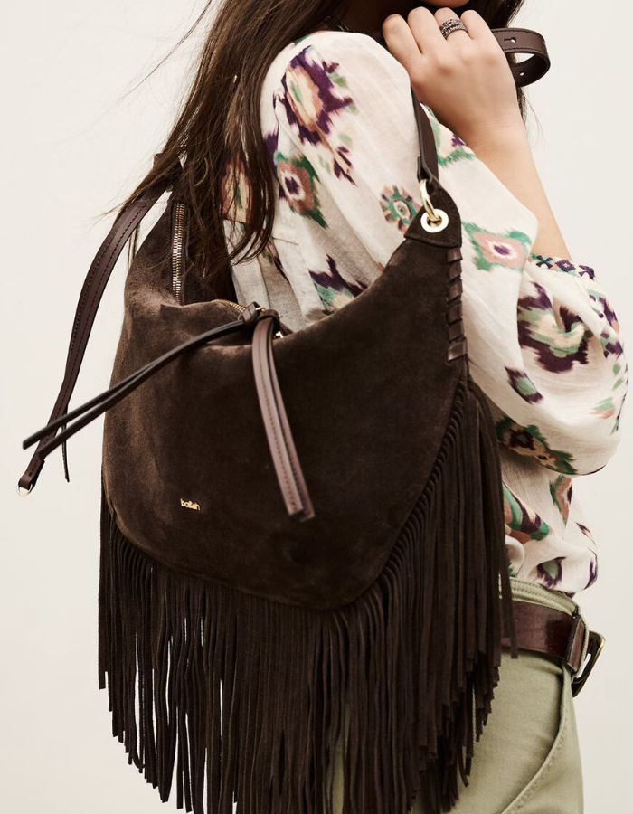Silhouette avec le Grand sac hobo pour femme de format XL en croûte de cuir marron chocolat, modèle Franges de la marque Ba&sh. De forme arrondie en demi-lune, le sac est doté d'une fermeture zippée et se caractérise par de très longues franges en cuir suspendues sur tout le bas de sa base.