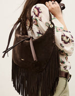 Silhouette avec le Grand sac hobo pour femme de format XL en croûte de cuir marron chocolat, modèle Franges de la marque Ba&sh. De forme arrondie en demi-lune, le sac est doté d'une fermeture zippée et se caractérise par de très longues franges en cuir suspendues sur tout le bas de sa base.