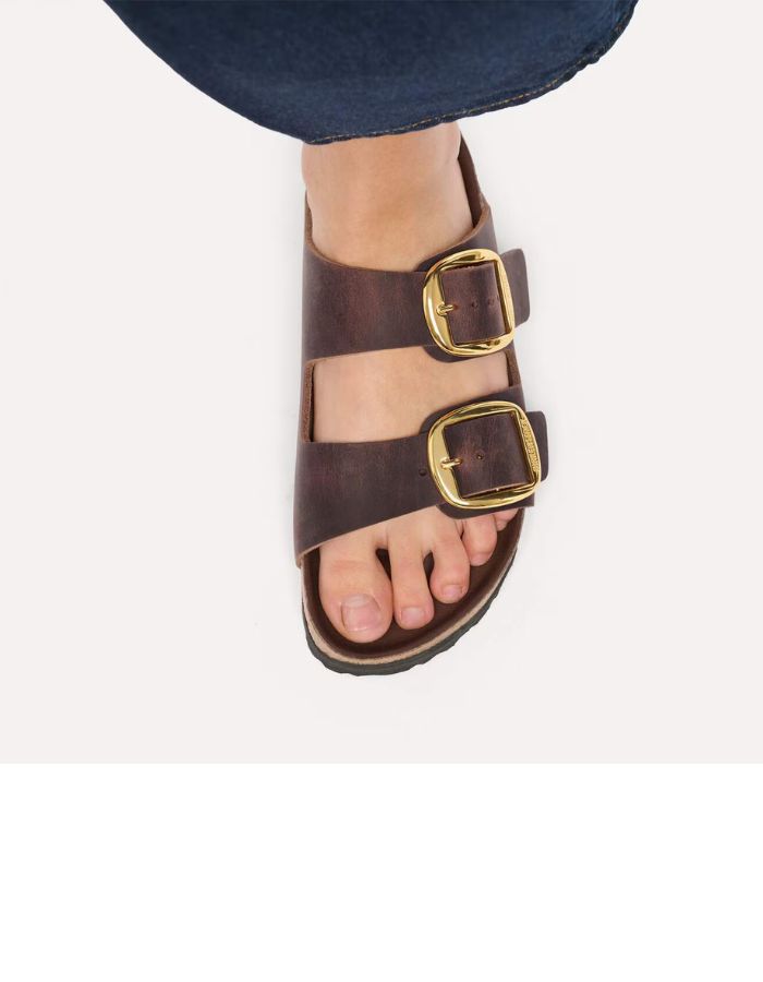 vue portée sur le dessus des Sandales Birkenstock modèle Arizona Big Buckle avec chaussant étroit. Présente deux larges brides en cuir huilé épais à bords bruts dotées de grandes boucles métalliques élégantes, montées sur la célèbre semelle anatomique en liège et cuir lisse assorti.