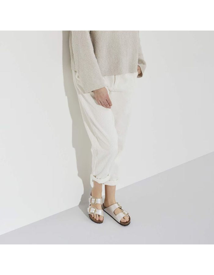 Vue de dessus des Sandales Birkenstock Arizona Big Buckle en largeur étroite. Les deux brides réglables sont en Birko-Flor® blanc nacré satiné (Graceful Pearl White) avec de grandes boucles en métal argenté, reposant sur une semelle anatomique en liège et cuir velours.