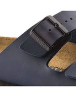 Boucle des Sandales pour homme et femme Arizona bleu de la marque BIRKENSTOCK en largeur étroite. Présentent deux brides ajustables en Birko-Flor® avec boucles métalliques et la semelle anatomique iconique en liège et cuir velours.