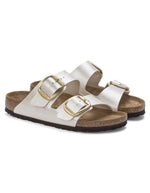 Paire de Sandales Birkenstock Arizona Big Buckle en largeur étroite. Les deux brides réglables sont en Birko-Flor® blanc nacré satiné (Graceful Pearl White) avec de grandes boucles en métal argenté, reposant sur une semelle anatomique en liège et cuir velours.