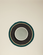 Set de table rond en raphia tressé main, noir, céladon et naturel, avec un bol céladon.