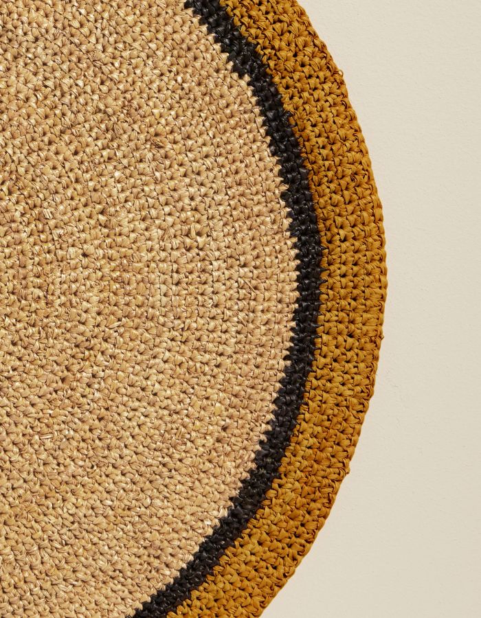 Détail du Set de table rond Globe par Maison Sarah Lavoine, confectionné en raphia naturel tressé à la main. Centre de couleur paille naturelle et bordure contrastée coloris jaune Safran. Design artisanal fabriqué à Madagascar, diamètre 38 cm