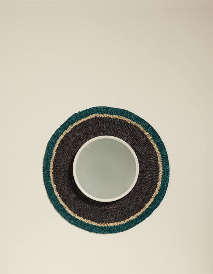 Set de table rond en raphia tressé main, noir, bleu Sarah et beige, avec un bol blanc.