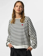 Vue de face du Sweatshirt à col rond et manches longues pour femme de couleur écru blanc cassé Cloud Dancer, modèle Greta de la marque PIECES. Présente une coupe classique droite avec un petit cœur noir brodé sur le côté gauche de la poitrine.