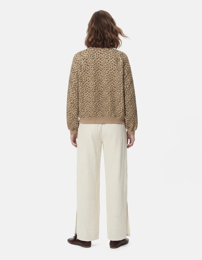 Silhouette de dos avec le Sweatshirt à col rond et manches longues pour femme avec un imprimé léopard noir et marron sur fond blanc cassé, modèle Greta de la marque PIECES. Présente une broderie rouge vif en forme de cœur sur le côté gauche de la poitrine.