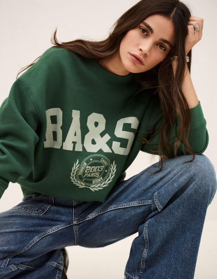 Mannequin portant un sweatshirt court ample vert émeraude Ba&sh avec logo et un jean décontracté.