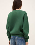 Dos d'une femme portant un sweatshirt Fenja Emeraude vert émeraude, coupe courte et ample, avec col rond.