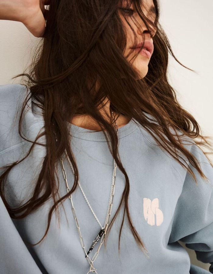 Col du Sweat-shirt pour femme en molleton doux de couleur bleu glacier pastel, modèle Swing de la marque Ba&sh. Présente une coupe ample loose avec col rond et manches raglan, rehaussée de surpiqûres overlock et d'une impression signature Ba&sh texturée sur la poitrine.