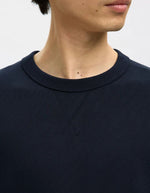 Col du Sweatshirt col rond pour homme en coton biologique bleu marine Navy, modèle Relaxluke de la marque SELECTED HOMME. Présente une coupe droite avec finition en bord-côte au col, aux poignets et à la taille.
