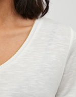 T-shirt col V blanc en jersey avec bordure dorée et manches courtes.