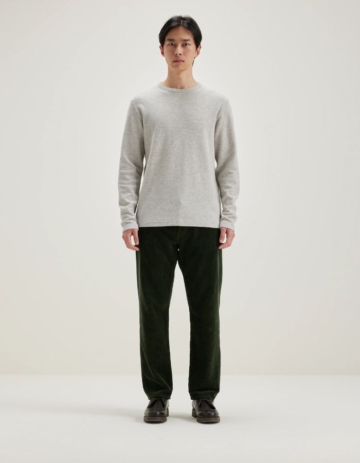 Homme portant un t-shirt gris clair en jersey double face à manches longues et un pantalon vert foncé.