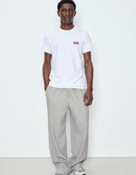 Silhouette avec le T-shirt à manches courtes pour homme de couleur blanc, modèle Ykobow de la marque American Vintage. Présente une coupe droite décontractée en coton doux avec un col rond et le logo American Vintage imprimé dans un style rétro sur la poitrine.