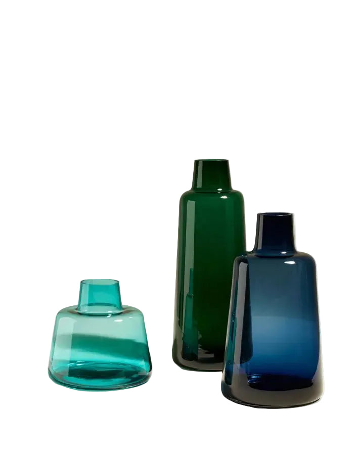 Trois vases Pures en verre teinté, vert émeraude et bleu nuit, aux formes architecturales et minimalistes.