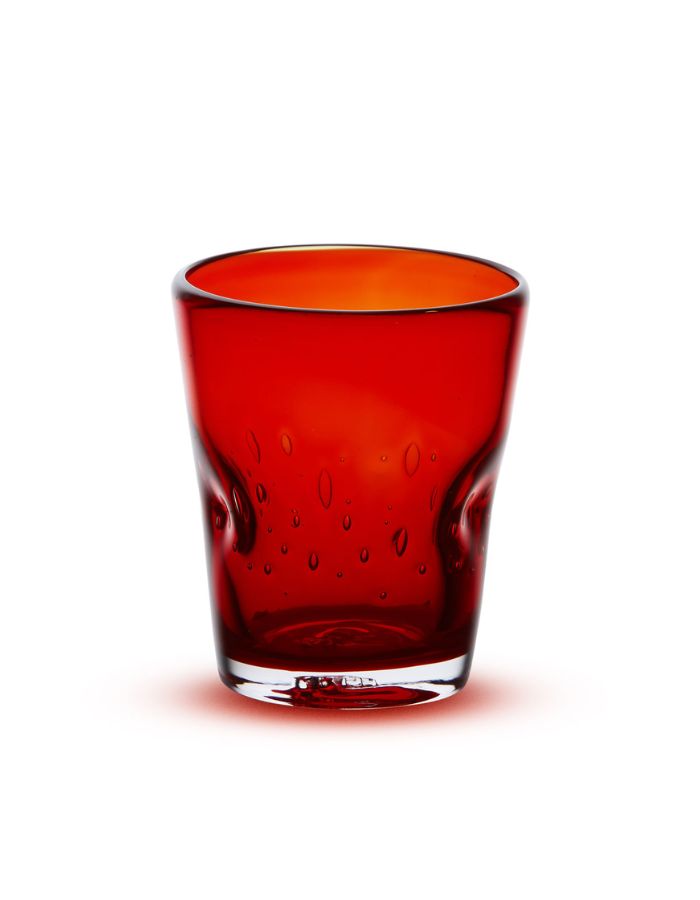 Verre à eau artisanal Memento Dune couleur rouge rubis, en verre soufflé à la bouche avec forme ergonomique ondulée et reflets brillants.