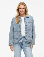 Femme souriante portant une veste en jean bleu clair Jaf avec col chemise, fermeture boutonnée et poches plaquées.