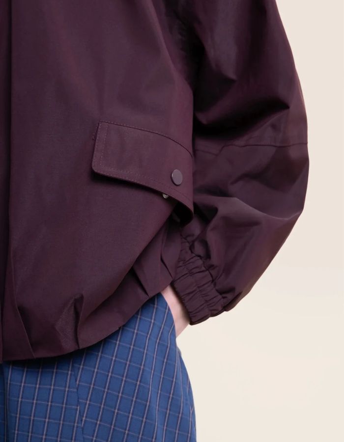 Manche de la Veste imperméable oversize mixte violette cassis avec détails plissés, effet bouffant et capuche amovible, modèle Garance couleur Cassis de la marque Flotte.