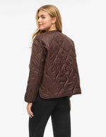 Vue de dos de la Veste matelassée légère et courte pour femme de couleur marron chocolat, modèle Dune de la marque Vila. Présente un col en V, des manches longues, des poches plaquées à l'avant et une fermeture par boutons-pression.