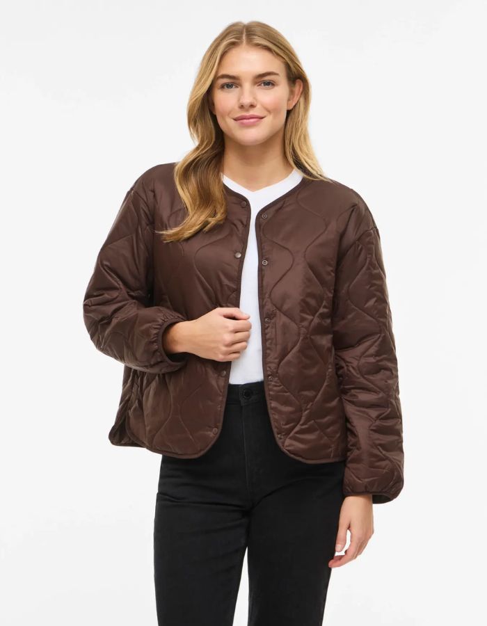 Vue de face avec la Veste matelassée légère et courte pour femme de couleur marron chocolat, modèle Dune de la marque Vila. Présente un col en V, des manches longues, des poches plaquées à l'avant et une fermeture par boutons-pression.