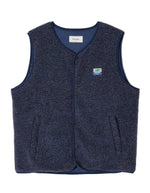 Veste sans manches pour homme de couleur bleu nuit foncé Astre Chiné, modèle Hoktown de la marque American Vintage. Confectionnée dans une matière épaisse effet mouton retourné shearling, elle présente un col montant bas, une fermeture à boutons-pression, deux poches zippées et un patch logo sur la poitrine.