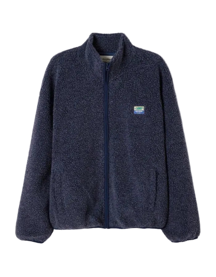 Veste zippée à manches longues pour homme de couleur bleu nuit foncé Astre Chiné, modèle Hoktown de la marque American Vintage. Confectionnée dans une matière épaisse effet mouton retourné shearling, elle présente un col montant bas, une fermeture éclair, deux poches zippées et un écusson logo AMV sur la poitrine.