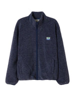 Veste zippée à manches longues pour homme de couleur bleu nuit foncé Astre Chiné, modèle Hoktown de la marque American Vintage. Confectionnée dans une matière épaisse effet mouton retourné shearling, elle présente un col montant bas, une fermeture éclair, deux poches zippées et un écusson logo AMV sur la poitrine.