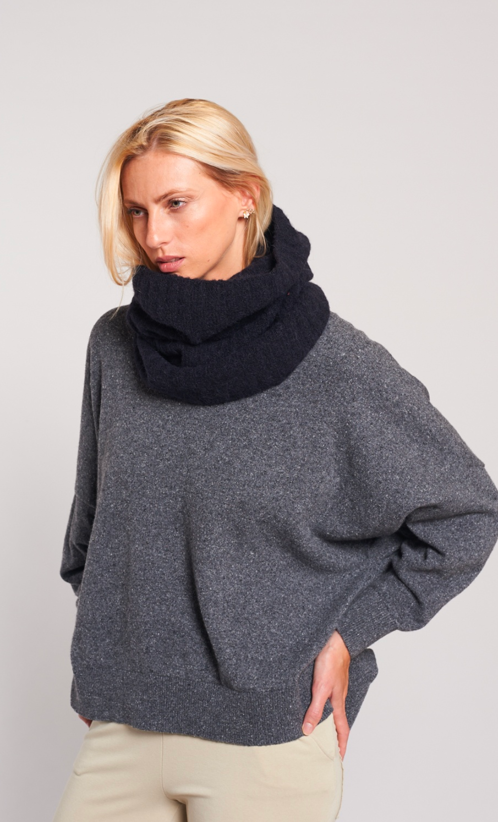 Femme portant un snood noir en alpaga doux et chaud, avec un pull gris et un pantalon beige.