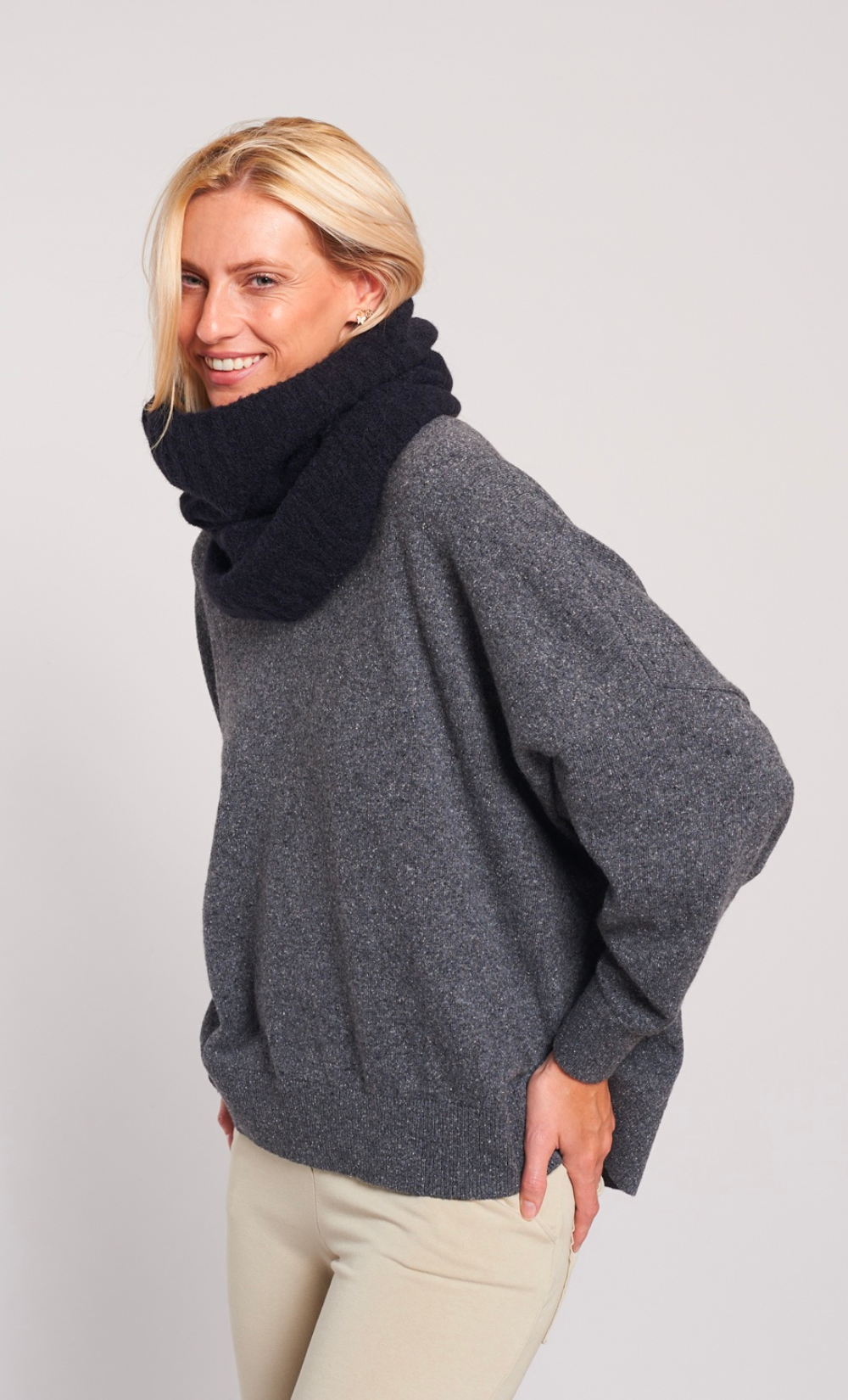 Femme souriante portant un snood noir en alpaga doux et un pull gris.