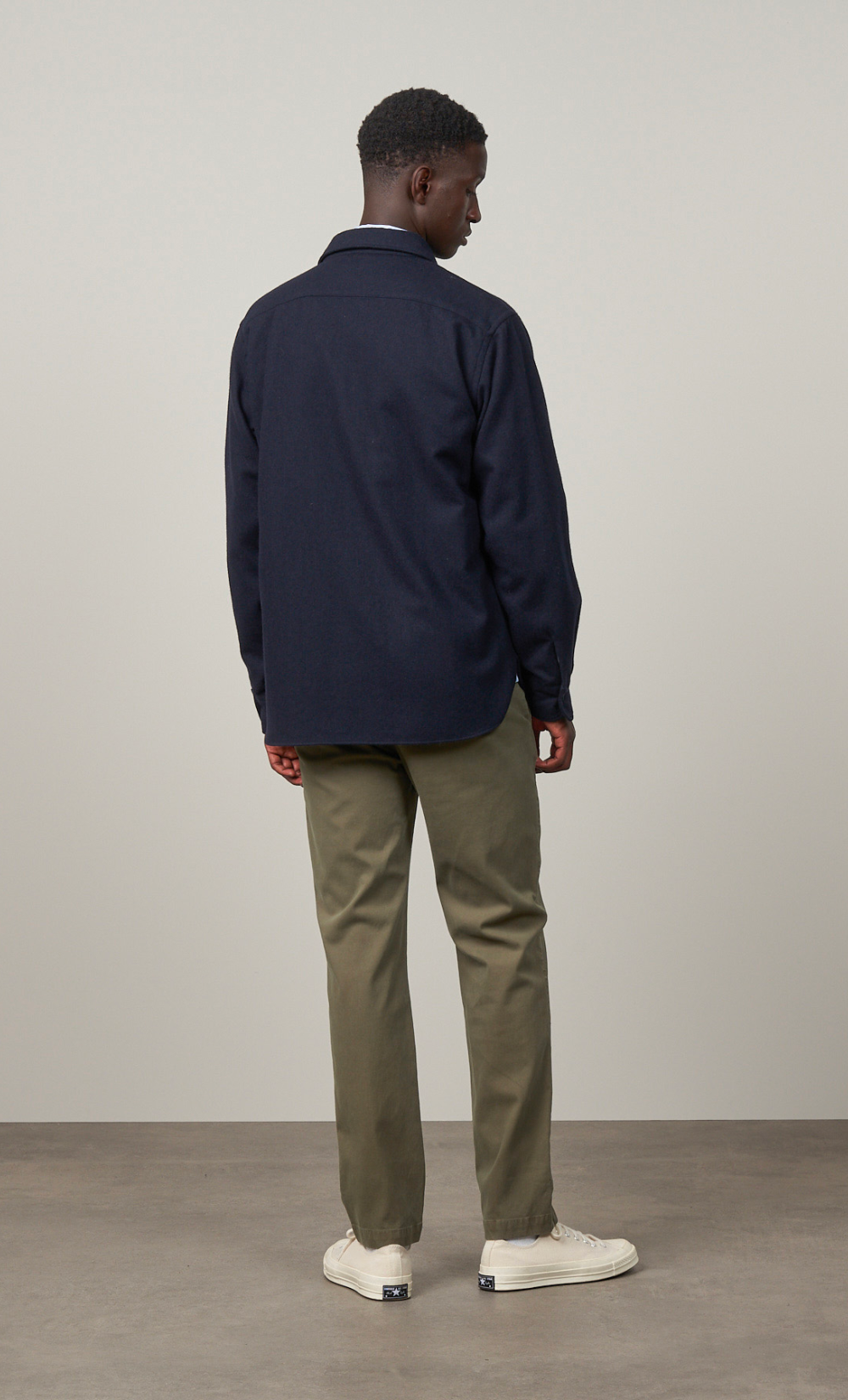 Homme de dos portant une surchemise Percey bleu marine en laine recyclée et un pantalon kaki.