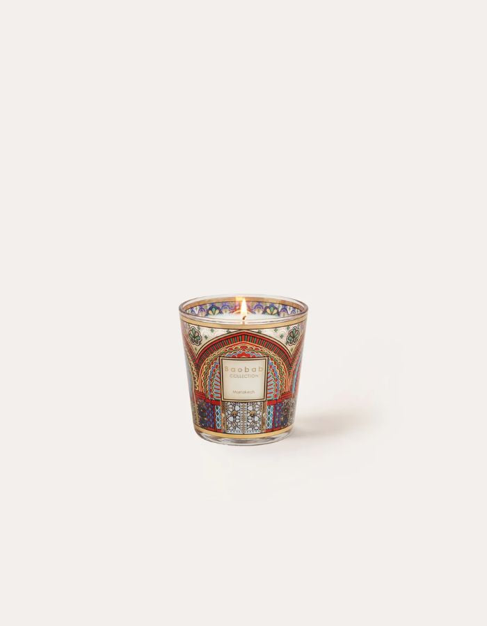 Bougie parfumée My First Baobab Marrakech en verre coloré avec motifs architecturaux mauresques et flamme allumée.