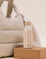 Photo d'ambiance avec la Bouteille isotherme ultra-compacte en inox recyclé couleur beige mat lin avec bouchon étanche en inox, modèle Icon Allure de la marque QWETCH.