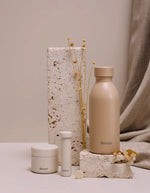 Photo d'ambiance avec la Bouteille isotherme ultra-compacte en inox recyclé couleur beige mat lin avec bouchon étanche en inox, modèle Icon de la marque QWETCH
