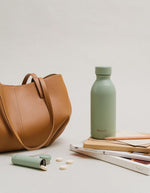 Photo d'ambiance avec la Bouteille isotherme ultra-compacte en inox recyclé couleur vert tilleul pastel avec bouchon étanche en inox, modèle Icon de la marque QWETCH