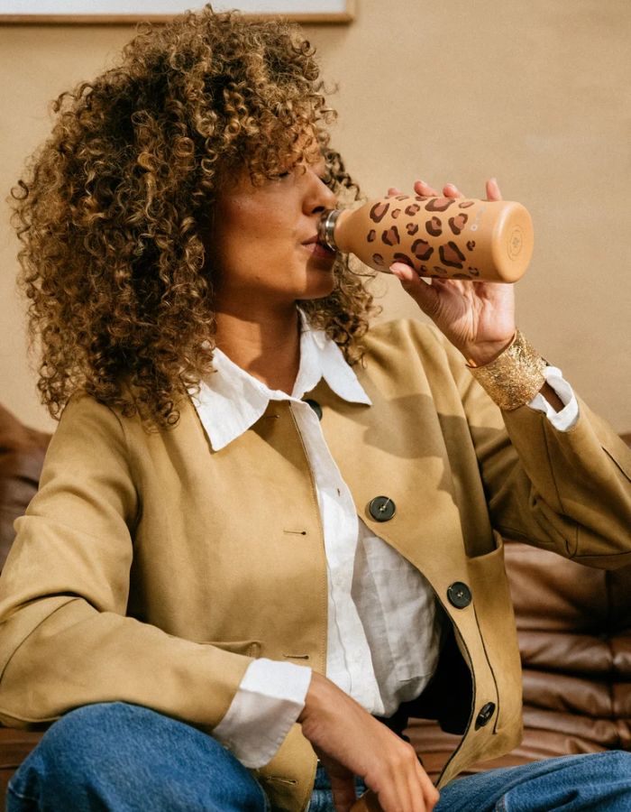 Photo d'ambiance avec la Bouteille isotherme ultra-compacte en inox recyclé avec motif léopard wild camel et bouchon étanche assorti, modèle Icon de la marque QWETCH