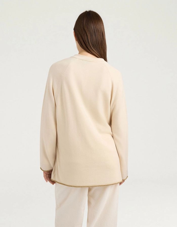 Vue de dos du Cardigan à col rond pour femme en pure laine crème, modèle Klak Bis de la marque MOMONI. Présente des manches raglan amples, une fermeture à ruban de laine à nouer et des liserés en lurex doré.