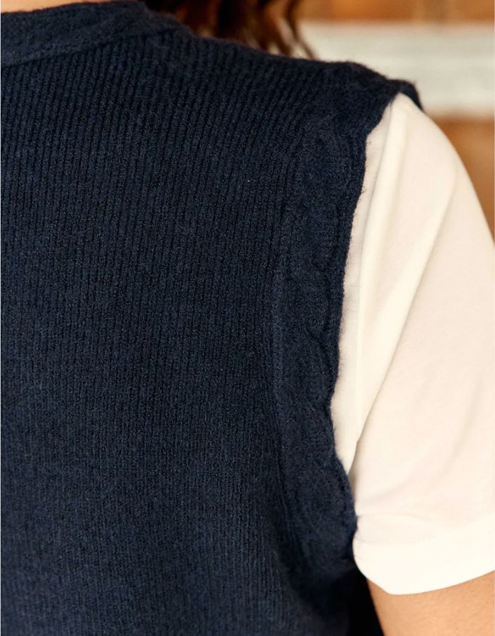 Epaule du Gilet sans manches pour femme en maille bleu marine à col V et boutons en corne, modèle Melba de La Petite Étoile. Présente des finitions torsadées au col, aux emmanchures et au bas.