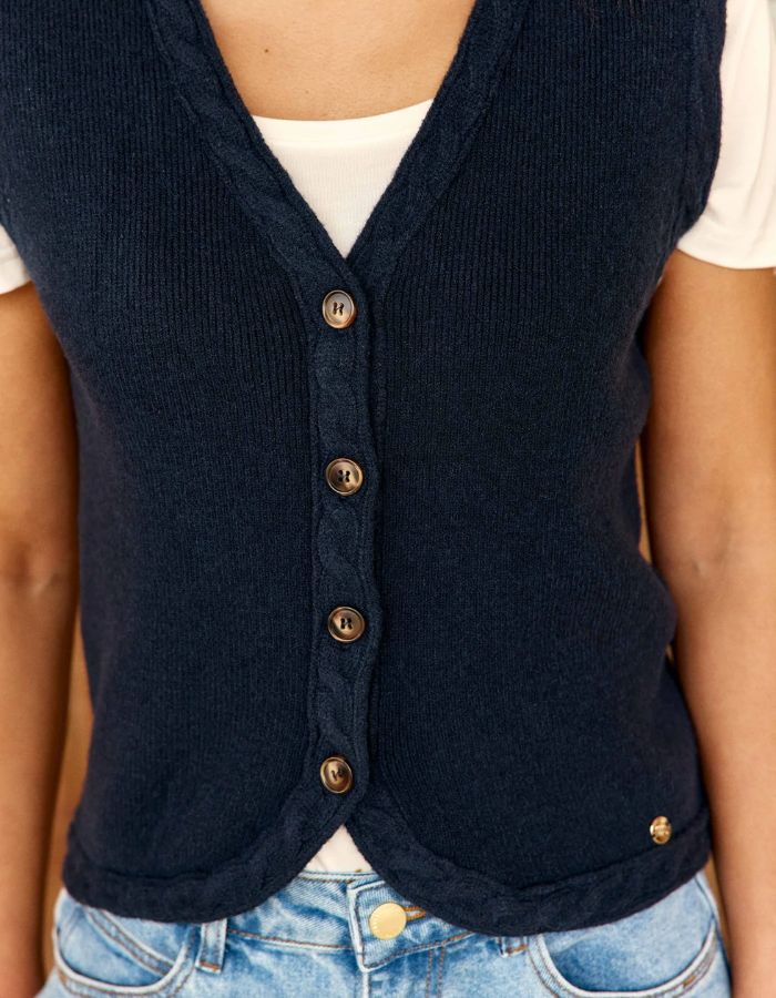 Vue de face du Gilet sans manches pour femme en maille bleu marine à col V et boutons en corne, modèle Melba de La Petite Étoile. Présente des finitions torsadées au col, aux emmanchures et au bas.