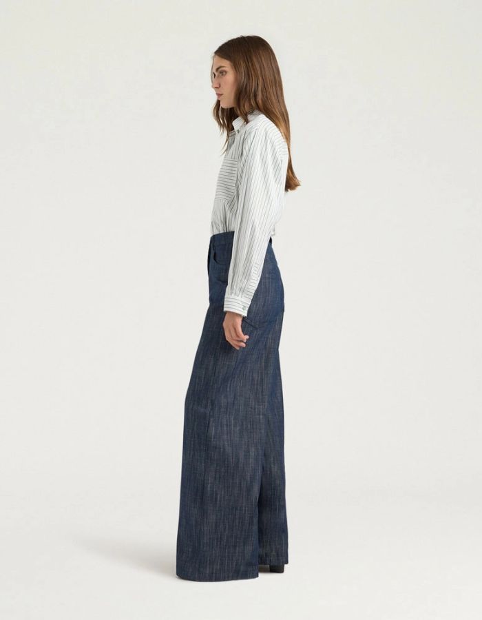Profil du Pantalon 5 poches en jean droit bleu pour femme, modèle Aoki de la marque MOMONI. Présente une fermeture par bouton clou, un passepoil en M au dos et une étiquette en cuir.