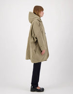 Profil de la Parka courte oversize pour femme en coton imperméable couleur taupe avec capuche, modèle Paola de la marque Prêt Pour Partir.