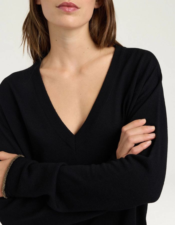 Col du Pull pour femme en pure laine noire, modèle Astrid de la marque MOMONI. Présente une maille teinté en pièce et de délicates bordures en lurex doré aux finitions.